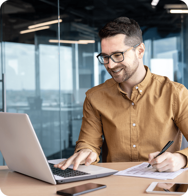 Man smiling while working on a laptop.